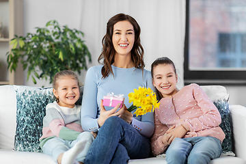 Image showing daughters giving flowers and gift to happy mother