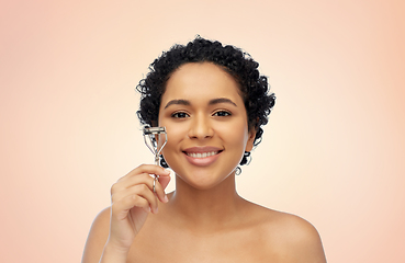 Image showing smiling african american woman with eyelash curler