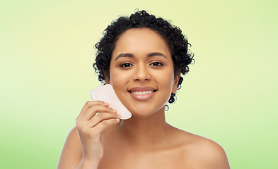 Image showing happy woman massaging her face with gua sha tool