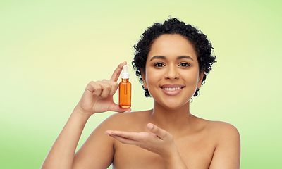 Image showing happy african american woman with bottle of serum