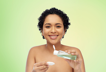 Image showing happy african woman with cotton pad an lotion