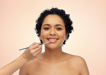 Image showing happy woman and hand of make up artist with brush