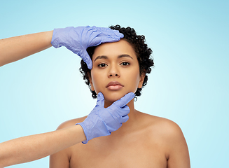 Image showing face of african woman and hands in medical gloves