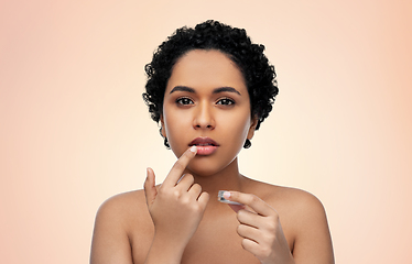 Image showing african american woman applying lip gloss