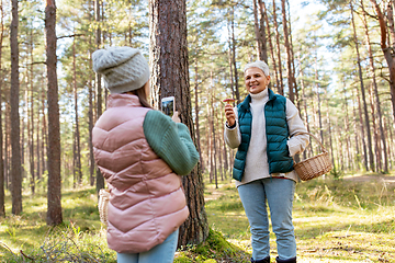 Image showing granddaughter photographing grandma with mushrooms