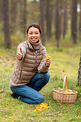 Image showing woman with mushrooms showing thumbs up in forest