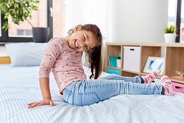 Image showing happy smiling little girl sitting on bed at home