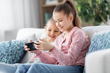 Image showing happy little girls or sisters with phone at home