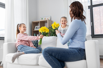 Image showing daughters giving daffodil flowers to happy mother