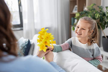 Image showing happy daughter giving daffodil flowers to mother