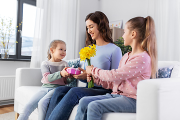 Image showing daughters giving flowers and gift to happy mother