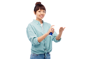 Image showing happy smiling asian woman using hand sanitizer