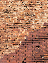 Image showing restored by modern brick, part of the old wall of a building made of red brick, close-up with a curving line of restoration