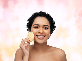 Image showing young woman cleaning face with exfoliating sponge