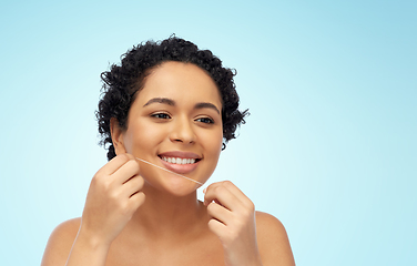 Image showing african woman cleaning teeth with dental floss