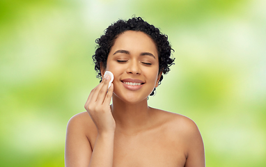 Image showing happy african woman cleaning face with cotton pad