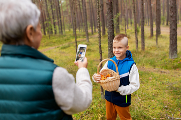 Image showing grandmother photographing grandson with mushrooms