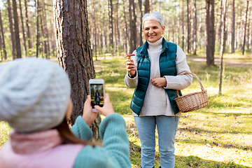 Image showing granddaughter photographing grandma with mushrooms