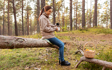 Image showing asian woman with mushrooms drinking tea in forest