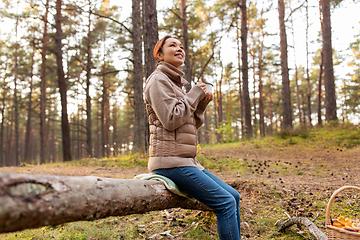 Image showing asian woman with mushrooms drinking tea in forest