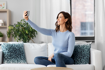 Image showing happy woman with smartphone taking selfie at home