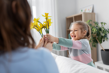 Image showing happy daughter giving daffodil flowers to mother