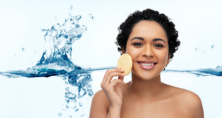 Image showing young woman cleaning face with exfoliating sponge