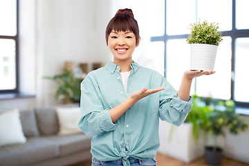 Image showing happy smiling asian woman holding flower in pot