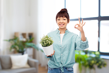 Image showing happy smiling asian woman holding flower in pot