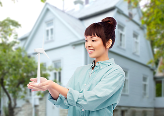 Image showing smiling young asian woman with toy wind turbine