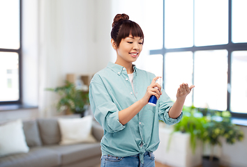 Image showing happy smiling asian woman using hand sanitizer