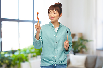 Image showing asian woman with wooden and plastic toothbrushes