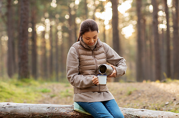 Image showing asian woman with thermos drinking tea in forest