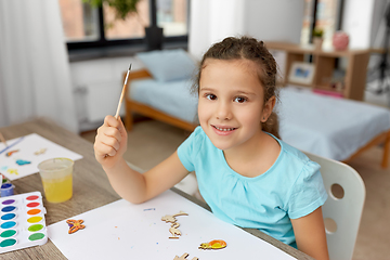 Image showing little girl painting wooden items at home