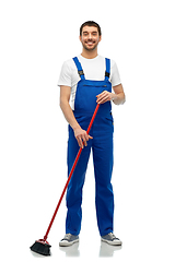 Image showing male cleaner in overall cleaning floor with broom