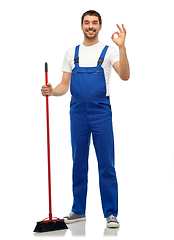 Image showing male cleaner in overall cleaning floor with broom