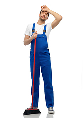 Image showing tired male cleaner cleaning floor with broom