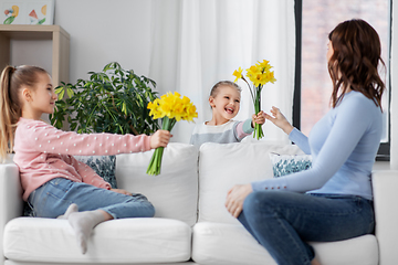 Image showing daughters giving daffodil flowers to happy mother