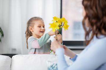 Image showing happy daughter giving daffodil flowers to mother