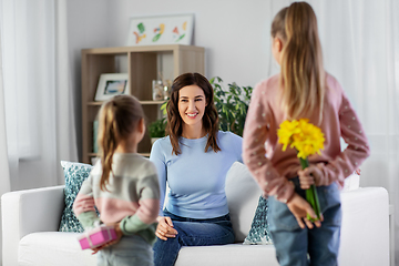 Image showing daughters giving flowers and gift to happy mother