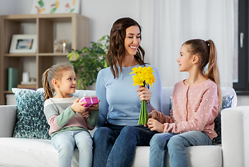 Image showing daughters giving flowers and gift to happy mother