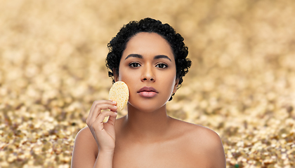 Image showing young woman cleaning face with exfoliating sponge