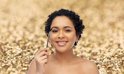 Image showing smiling african american woman with mascara brush