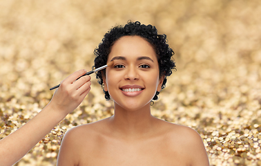 Image showing happy woman and hand of make up artist with brush