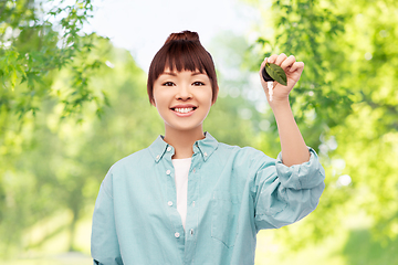 Image showing happy asian woman holding car key with green leaf