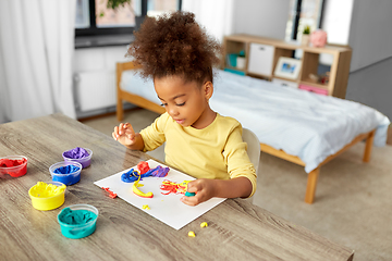 Image showing little girl with modeling clay playing at home