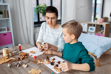 Image showing mother and son making pictures of autumn leaves