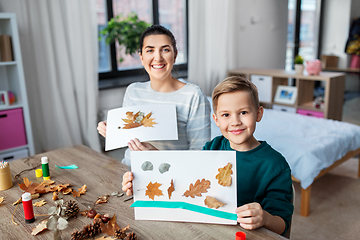 Image showing mother and son making pictures of autumn leaves