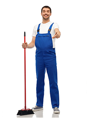 Image showing male cleaner in overall cleaning floor with broom