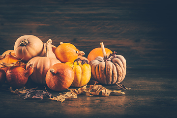 Image showing Assortment of pumpkins with autumn leaves on wooden background